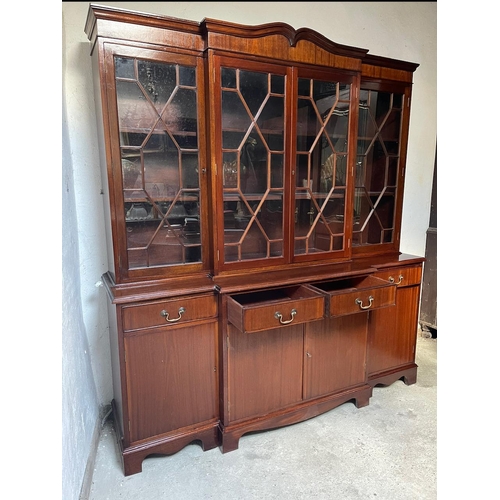 48 - A GOOD QUALITY IRISH MAHOGANY BREAK-FRONT LIBRARY BOOKCASE, the pediment with curved detail to the c... 