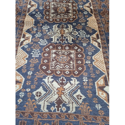 106 - AN AFGHAN BELOUCH FLOOR RUG, with overall ground colour blue; to the outside border are floral shape... 