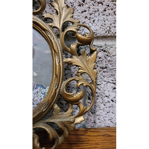 125 - A PAIR OF ANTIQUE GILT CAST METAL PICTURE FRAMES, each with scrolling foliage design, the rim of the... 