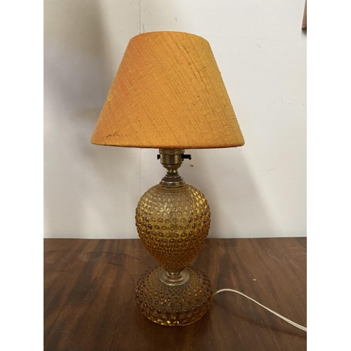 182 - A DECORATIVE AMBER GLASS GILT TABLE LAMP, with shaped support atop circular platform base and fringe... 