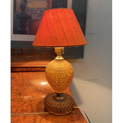 182 - A DECORATIVE AMBER GLASS GILT TABLE LAMP, with shaped support atop circular platform base and fringe... 