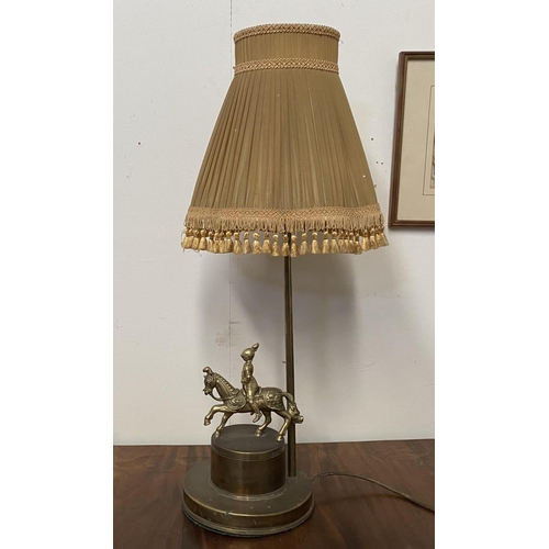 183 - A VINTAGE BRASS TABLE LAMP, with horse and solider atop circular platform base, complete with fringe... 