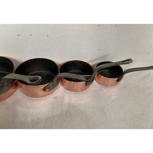 189 - A GOOD QUALITY SET OF SIX COPPER SAUCEPANS, each with a heavy cast iron handle with lopped tip to ai... 