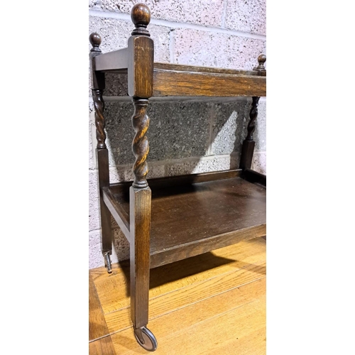 199 - AN ANTIQUE MAHOGANY DRINKS TROLLEY, with two tiers, twist supports with finials to top on castors. D... 