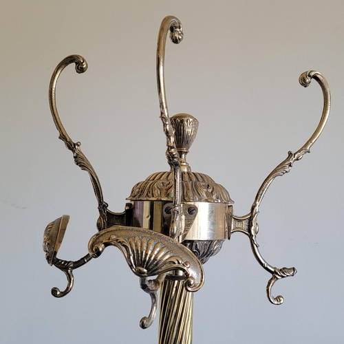 219 - A BRASS HALL COAT STAND, with three scrolling hooks to the top, two with shell ends, raised on a bar... 