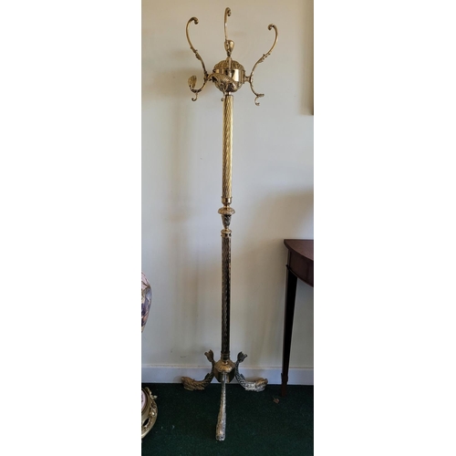 219 - A BRASS HALL COAT STAND, with three scrolling hooks to the top, two with shell ends, raised on a bar... 