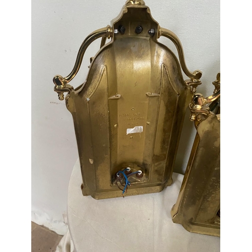 27 - A VERY GOOD QUALITY TRIO OF POLISHED BRASS WALL LANTERN LIGHTS, each with a triple bulb head the bac... 