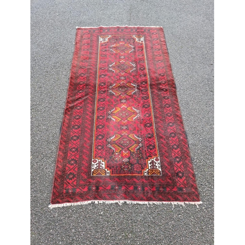 43 - A GOOD QUALITY PERSIAN MASHAD BELOUCH FLOOR RUG, over all ground colour red, with highlights in must... 