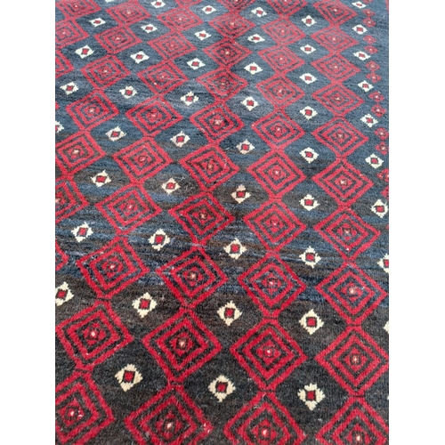 63 - A VERY GOOD QUALITY PERSIAN MASHAD BELOUCH FLOOR RUG, with a repeat diamond motif to the centre surr... 