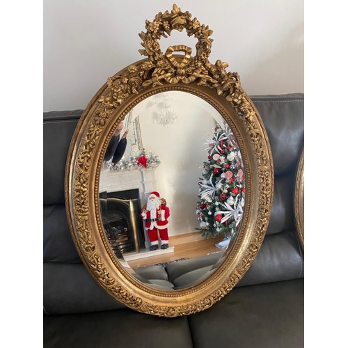 77 - A VERY FINE PAIR OF GILT OVAL SHAPED WALL MIRRORS, the mirrors with bevelled edge, the frames decora... 