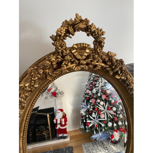 77 - A VERY FINE PAIR OF GILT OVAL SHAPED WALL MIRRORS, the mirrors with bevelled edge, the frames decora... 