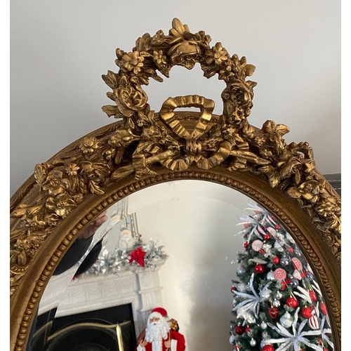 77 - A VERY FINE PAIR OF GILT OVAL SHAPED WALL MIRRORS, the mirrors with bevelled edge, the frames decora... 