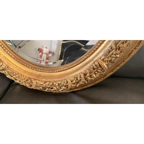 77 - A VERY FINE PAIR OF GILT OVAL SHAPED WALL MIRRORS, the mirrors with bevelled edge, the frames decora... 