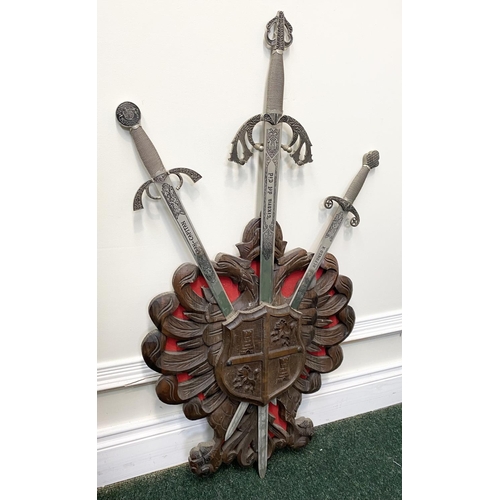 95 - A VINTAGE CARVED WALL-MOUNTED PLAQUE, featuring three Toledo engraved swords, with silver finish, cy... 