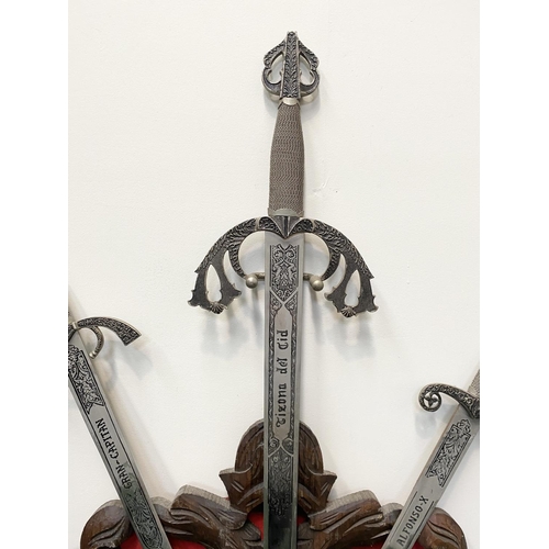 95 - A VINTAGE CARVED WALL-MOUNTED PLAQUE, featuring three Toledo engraved swords, with silver finish, cy... 