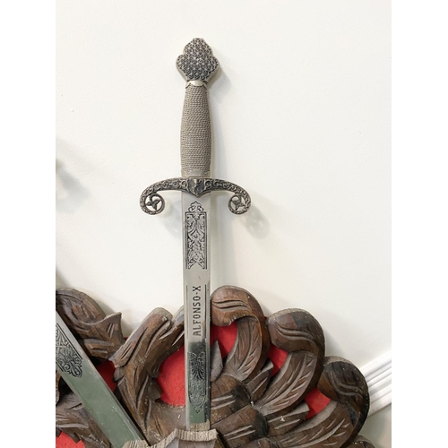 95 - A VINTAGE CARVED WALL-MOUNTED PLAQUE, featuring three Toledo engraved swords, with silver finish, cy... 