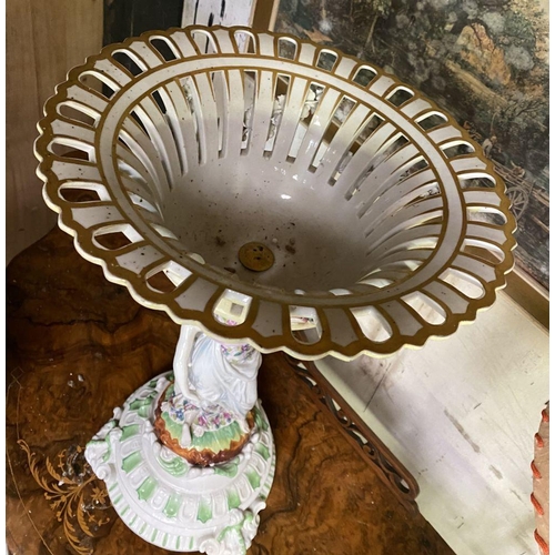 103 - A LARGE PORCELAIN COMPOTE CENTREPIECE, with flower encrusted basket, female figures to column standi... 