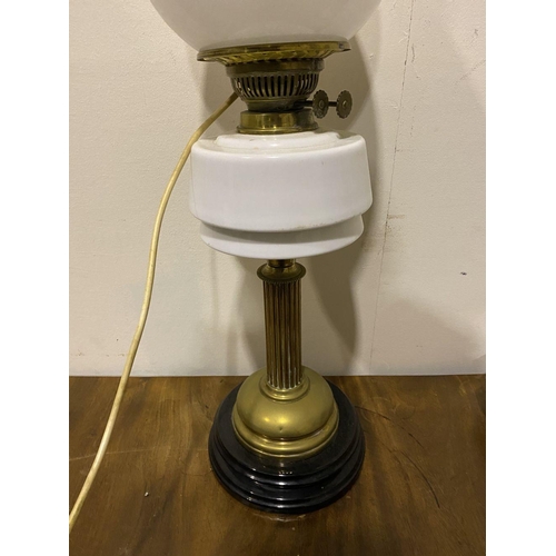 121 - A VINTAGE BRASS OIL LAMP, with two white glass shades, and chimney marked ‘Fire Proof’, with duplex ... 