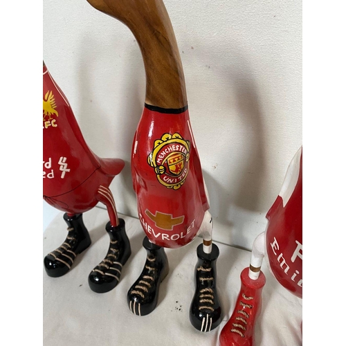 129 - A SET OF FOUR HARDWOOD DUCK FIGURINES, with painted soccer jerseys, dimensions: 50cm high approx.