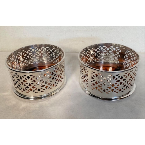 23 - A PAIR OF CIRCULAR SILVER PLATED WINE COASTERS, with pierced design surrounding, as well as inlaid t... 