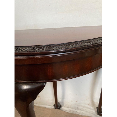 31 - A MAHOGANY HALF MOON CARD TABLE, with carving to edge, opening to green baize lined interior, standi... 