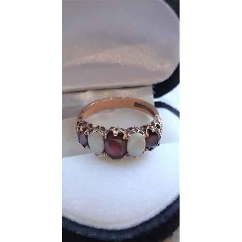 7 - A DECORATIVE 9CT GOLD GEMSET RING, ring set with opals and red stones in decorative setting. Weight:... 