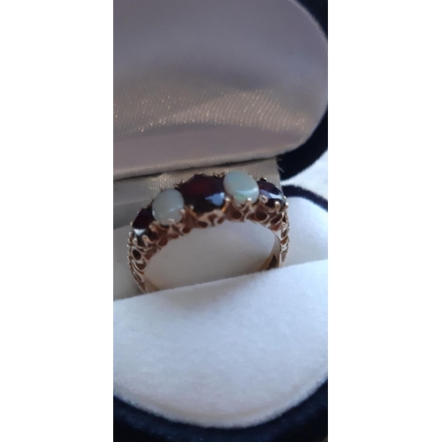 7 - A DECORATIVE 9CT GOLD GEMSET RING, ring set with opals and red stones in decorative setting. Weight:... 