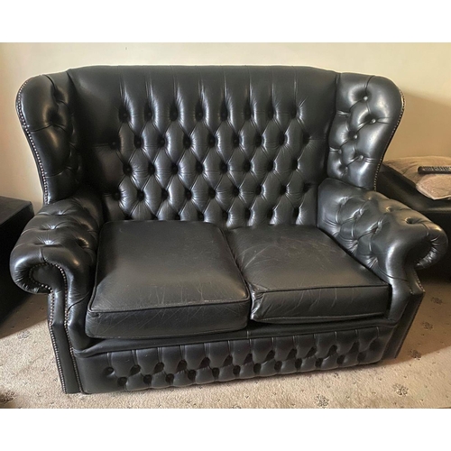 72 - A BLACK LEATHER CHESTERFIELD TWO SEATER ARMCHAIR, with button back, scroll armrests on platform base... 