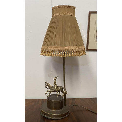 99 - A VINTAGE BRASS TABLE LAMP, with horse and solider atop circular platform base, complete with fringe... 