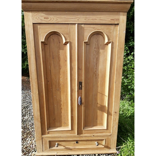 135 - A VICTORIAN STRIPPED PINE TWO DRAWER WARDROBE, with dentil cornice above arched panelled doors and o... 