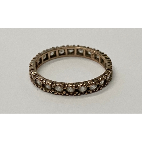 27 - A 9CT YELLOW GOLD ETERNITY RING, set with clear round cut stones in shared print setting. Ring Size:... 