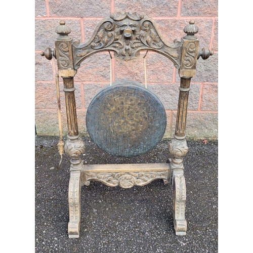 121 - A 19TH CENTURY OAK JACOBEAN STYLE DINNING GONG & STAND, the stand with central 'Greenman' head to th... 