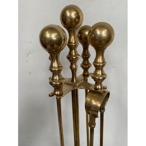 133 - A SET OF FOUR BRASS FIRE IRONS ON STAND, decorative gilt brass, to include poker, shovel, tongs and ... 