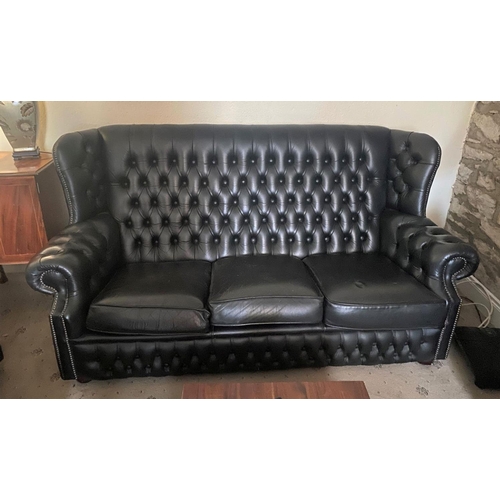 239 - A FINE BLACK LEATHER CHESTERFIELD THREE SEATER ARMCHAIR, with button back, scroll armrests on platfo... 