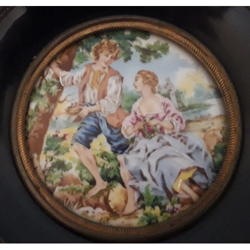 51 - A CIRCULAR FRAMED MINIATURE PAINTING ON PORCELAIN, depicting courting couple within garden. Dimensio... 