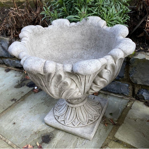 6 - A PAIR OF STONE GARDEN URNS, with turned lip above leaf design to body supported by square platform ... 