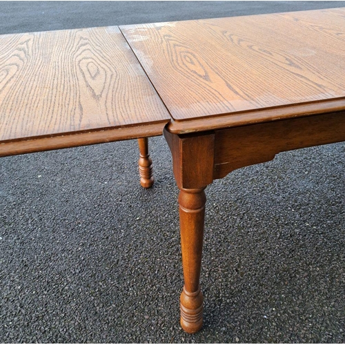 232 - A VINTAGE OAK DRAW-LEAF/EXTENDABLE DINING TABLE on turned legs; note damage to the finish on top of ... 