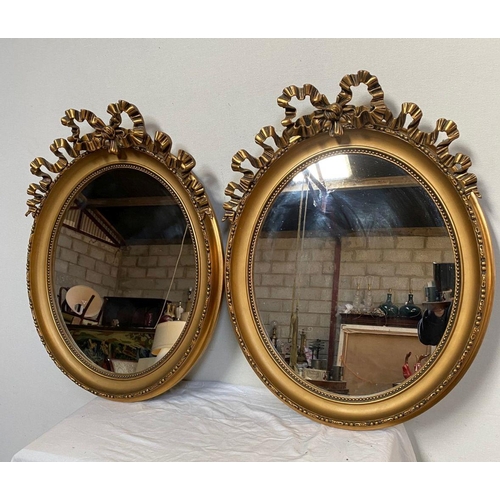 26 - A PAIR OF DECORATIVE OVAL GILT OVERMANTLE MIRRORS, with beading to gilt frame, bow mounting to top w... 