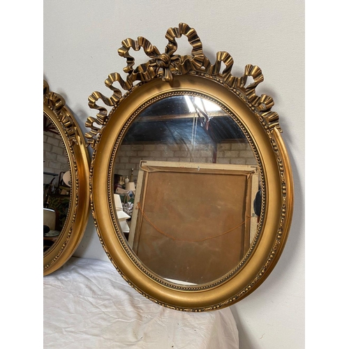 26 - A PAIR OF DECORATIVE OVAL GILT OVERMANTLE MIRRORS, with beading to gilt frame, bow mounting to top w... 