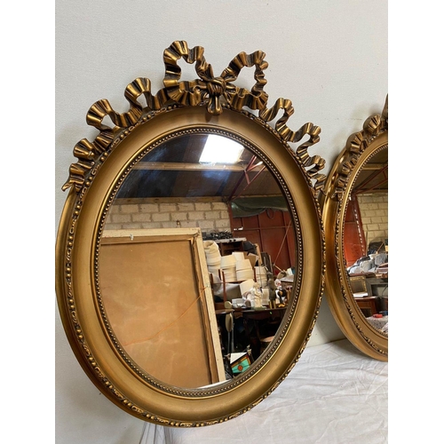 26 - A PAIR OF DECORATIVE OVAL GILT OVERMANTLE MIRRORS, with beading to gilt frame, bow mounting to top w... 