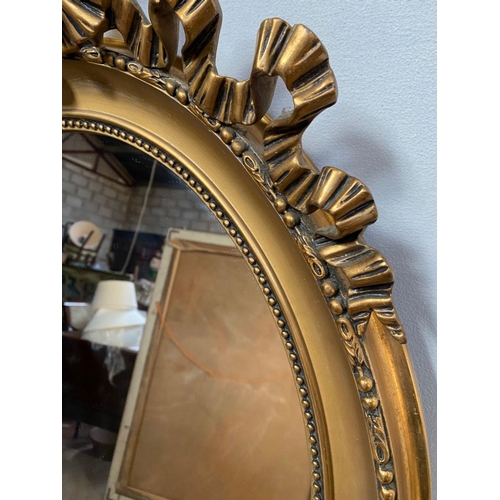 26 - A PAIR OF DECORATIVE OVAL GILT OVERMANTLE MIRRORS, with beading to gilt frame, bow mounting to top w... 