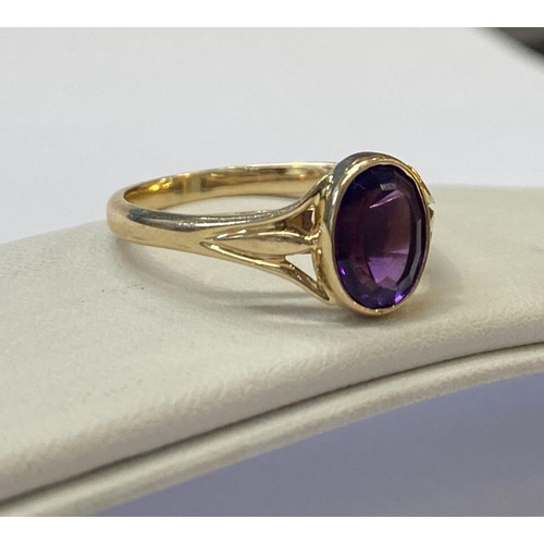 48 - AN ELEGANT 14CT YELLOW GOLD BEZEL AMETHYST RING, oval cut amethyst bezel set with split shank design... 