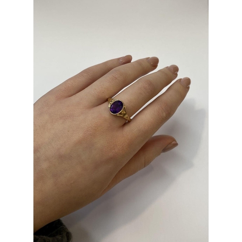 48 - AN ELEGANT 14CT YELLOW GOLD BEZEL AMETHYST RING, oval cut amethyst bezel set with split shank design... 