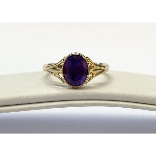 48 - AN ELEGANT 14CT YELLOW GOLD BEZEL AMETHYST RING, oval cut amethyst bezel set with split shank design... 