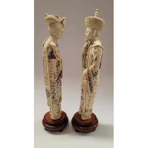 138 - A PAIR OF CARVED CHINESE FIGURES IN THE FORM OF AN EMPEROR & EMPRESS, each with etched design to the... 