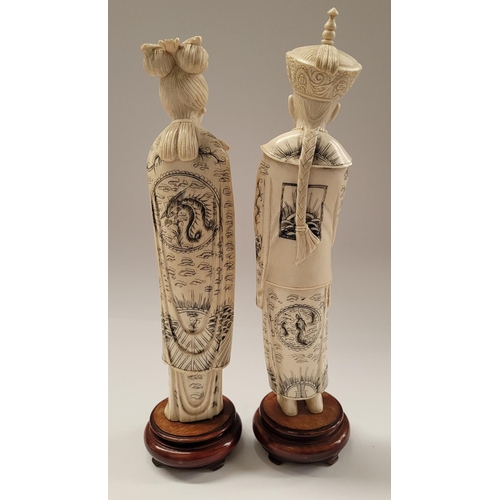 138 - A PAIR OF CARVED CHINESE FIGURES IN THE FORM OF AN EMPEROR & EMPRESS, each with etched design to the... 