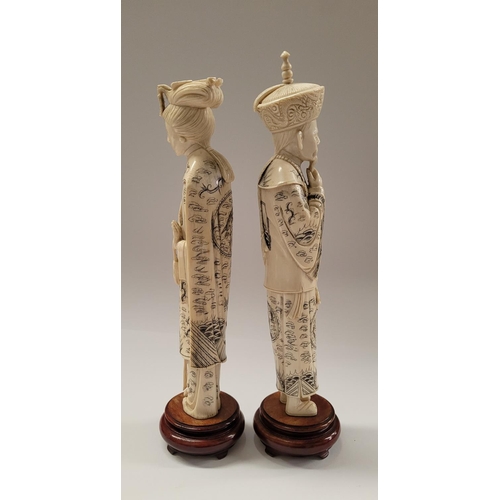 138 - A PAIR OF CARVED CHINESE FIGURES IN THE FORM OF AN EMPEROR & EMPRESS, each with etched design to the... 