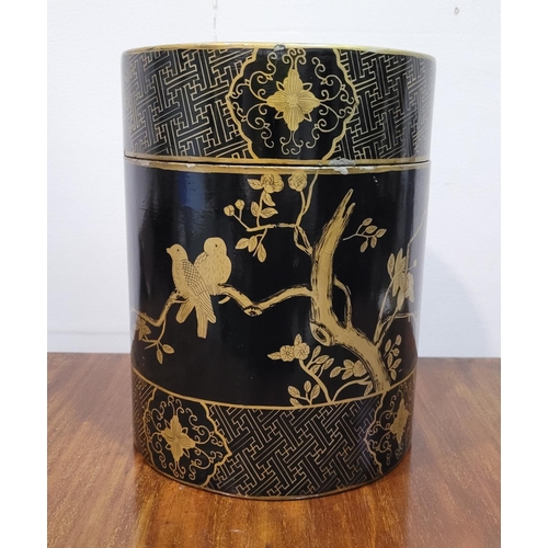 141 - A TALL CYLINDRICAL CHINESE LAQUERED LIDDED BOX, the box decorated all over with gilt coloured birds ... 