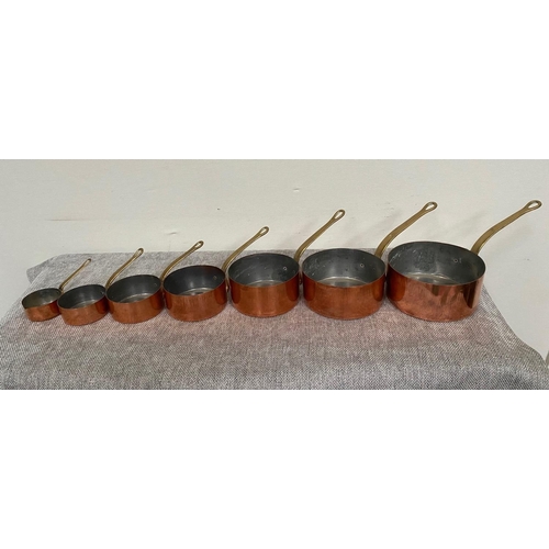 151 - A VERY GOOD SET OF SEVEN COPPER SAUCEPANS, each with heavy brass handles.