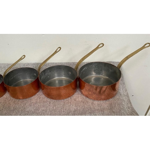 151 - A VERY GOOD SET OF SEVEN COPPER SAUCEPANS, each with heavy brass handles.